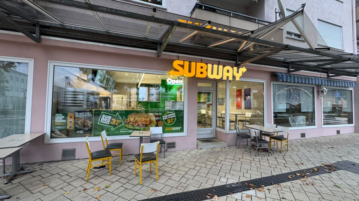 Subway Tuttlingen, Bahnhofstraße 156/158: beleuchtetes Logo über dem Eingang, Tische vor dem Laden