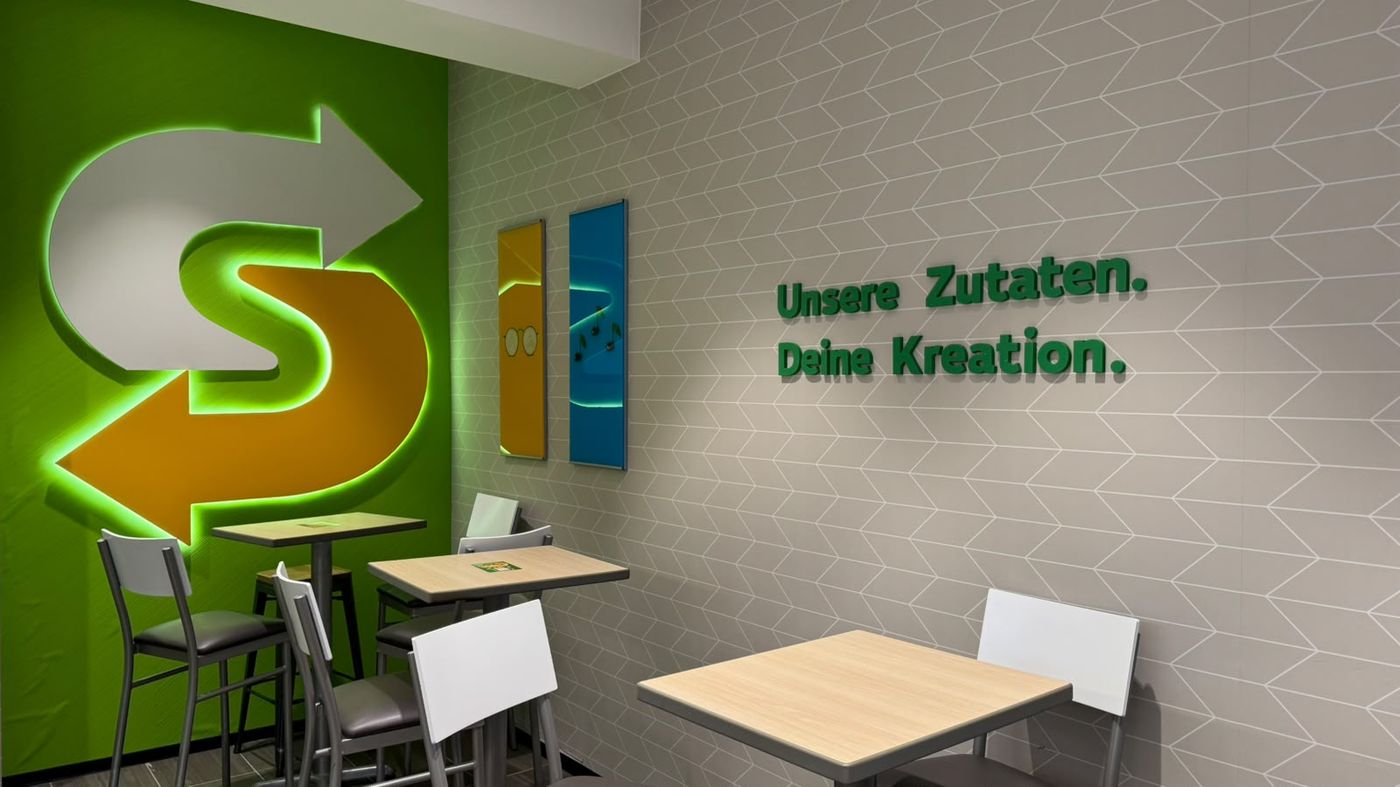 Sitzbereich mit beleuchtetem Logo an der grünen Wand